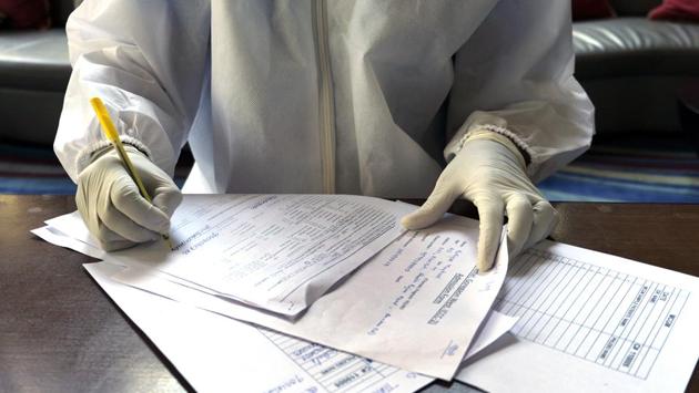 A doctor fills a form for Maqbool’s second swab test while he was is in quarantine, in Mumbai on April 24, 2020. Every morning there would be phone calls from the nurse or doctor on duty to check his health. (Rafiq Maqbool / AP) A doctor fills a form for Maqbool’s second swab test while he was is in quarantine, in Mumbai on April 24, 2020. Every morning there would be phone calls from the nurse or doctor on duty to check his health. (Rafiq Maqbool / AP)