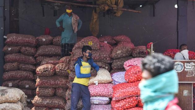 Workers look on during a health survey in Azadpur Mandi. The market has around 2,800 registered traders and around 12,000 individuals are engaged in various roles, such as accountants, porters, daily wage labourers engaged in loading and unloading of goods etc. (Sanchit Khanna / HT Photo)