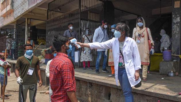 A medic conducts thermal screening for workers in Azadpur Mandi. As many as 15 traders in the market have tested positive for Covid-19 infection on Thursday and 43 contacts have been quarantined. Test results of over 100 persons associated with the market are awaited, while over 500 have been screened. (Sanchit Khanna / HT Photo)