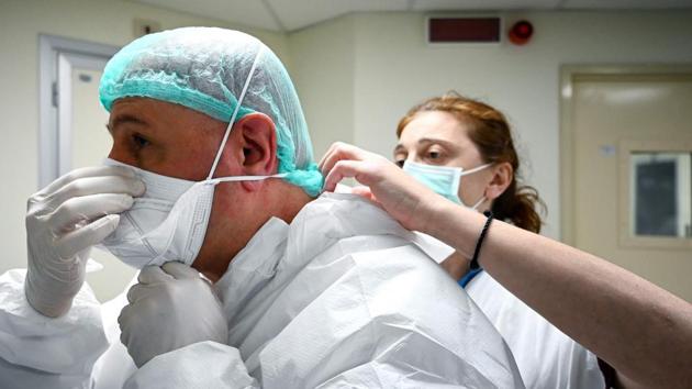 Marino De Rosa pinches his mask tight over the bridge of his nose as a nurse helps him put on his Personal Protective Equipment (PPE) before an afternoon shift in a COVID-19  unit in Rome. The 54-year old has a gruelling six hours ahead of him. Night shifts last 12 hours, though they are shared with another anaesthetist. (Alberto Pizzoli / AFP) 