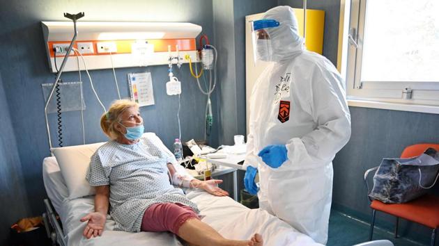 Anaesthesiologist Marino De Rosa speaks with a patient in the ICU of the Covid unit of the San Filippo Neri hospital, in Rome. “Patient contact is visual. We talk to them, they describe their symptoms. We have a tool that allows us to measure blood oxygen levels, which gives us an idea of the level of respiratory insufficiency,” De Rosa told AFP. (Alberto Pizzoli / AFP) 