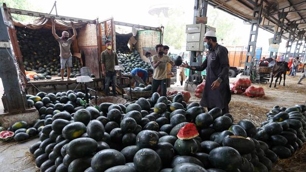 Workers unload watermelons from a truck in Azadpur Mandi. In regular times, at least 3,300 trucks supply produce to the Azadpur market every day, while the other two major agriculture produce markets in the city -- Ghazipur and Okhla -- receive around 400 and 200 trucks a day, respectively. (ANI)