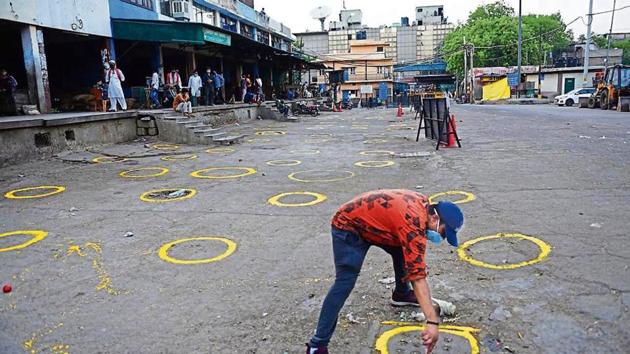 A worker marks circles for social distancing at Okhla Mandi on Saturday.