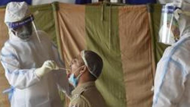 A medical worker collects swab from a police officer during a health camp organised for vegetable vendors and dealers, during extended nationwide lockdown to curb the spread of coronavirus, at Okhla wholesale vegetable market, in New Delhi.(Burhaan Kinu/HT PHOTO)