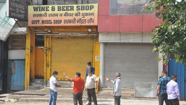 People seen outside a shuttered liquor shop during Covid-19 lockdown at New Bus adda in Ghaziabad on Monday.(Sakib Ali/HT File Photo)