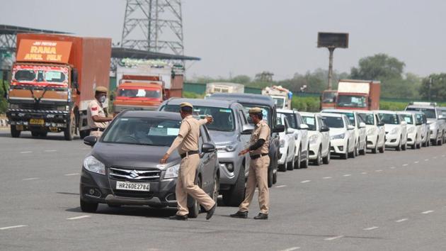 Haryana Police personnel screen commuters for identity cards and permits at the Delhi-Gurugram Border near Ambience Mall, in Gurugram.(Yogendra Kumar/HT PHOTO)
