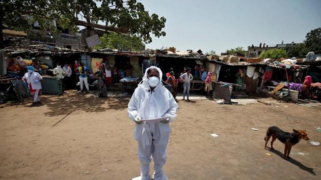A health worker wearing a protective gear announces names of people who were tested positive for the coronavirus disease (COVID-19) and will be taken to a quarantine facility, during an extended nationwide lockdown to slow the spreading of the disease, at a slum area in India.(REUTERS)