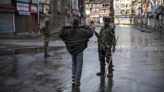 A security forces personnel conducts a check on a Kashmiri resident during a curfew in Srinagar, August 8, 2019. The image was part of a series of photographs by Associated Press photographers which won the 2020 Pulitzer Prize for Feature Photography. (Dar Yasin / AP)