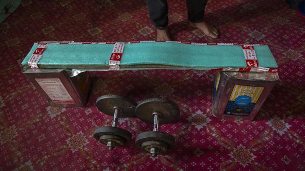 Weightlifter Bashir Ahmed has fashioned a makeshift bench of tin boxes and a wooden plank covered with thermocol inside his room in Srinagar. (Dar Yasin / AP)