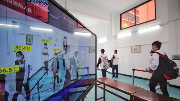 High school senior students walk past a thermal scanner in a school. Thermal scanners greeted everyone walking through school gates, and anyone with a high temperature was not allowed in. (AFP) High school senior students walk past a thermal scanner in a school. Thermal scanners greeted everyone walking through school gates, and anyone with a high temperature was not allowed in. (AFP)