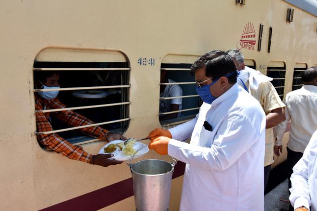 Hisar’s mayor Gautam Sardana distributing food to migrant labourers at local railway station on Thursday.(HT Photo)