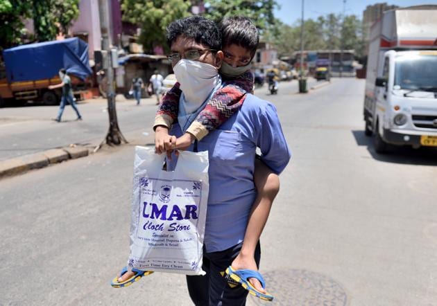 Kamarudeen Ansari carries his 8 year old son Ajamal Hussain on shoulder for medical treatment at KEM hospital from Dharavi , during the nationwide lockdown, imposed in the wake of the coronavirus pandemic in Mumbai, India.(Satish Bate/HT Photo)