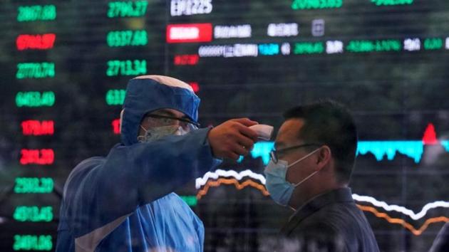 A worker wearing a protective suit takes body temperature measurement of a man inside the Shanghai Stock Exchange building, as the country is hit by the coronavirus outbreak, at the Pudong financial district in Shanghai, China. (REUTERS) A worker wearing a protective suit takes body temperature measurement of a man inside the Shanghai Stock Exchange building, as the country is hit by the coronavirus outbreak, at the Pudong financial district in Shanghai, China. (REUTERS)