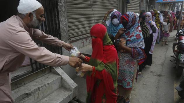 A man gives food to women for the Muslim fasting month of Ramzan, during a government-imposed Covid-19 lockdown in Lahore, Pakistan, on Wednesday. (AP) A man gives food to women for the Muslim fasting month of Ramzan, during a government-imposed Covid-19 lockdown in Lahore, Pakistan, on Wednesday. (AP)