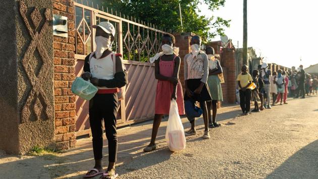 A queue of needy individuals with plates in hand forms outside Samantha Murozoki's home in Chitungwizaon May 5, 2020, where she feeds the underprivileged a free meal during the government imposed Covid-19 coronavirus lockdown period in Zimbabwe.(AFP photo)