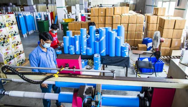 A worker wearing a protective mask operates a tape cutting machine while producing adhesive sealing tapes at a factory in Sonipat district, Haryana (Bloomberg Photo)
