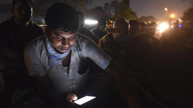 A migrant workers checks his phone in the night on the Eastern Express Highway between Thane and Bhiwandi in Mumbai. (Satish Bate / HT Photo) A migrant workers checks his phone in the night on the Eastern Express Highway between Thane and Bhiwandi in Mumbai. (Satish Bate / HT Photo)