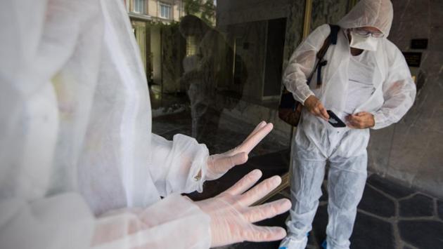 Alain (R) and Loriane (L), a psychiatrist, both wearing protective suits -- prepare to visit a young man with autism at his home, because he cannot be hosted at Elan Retrouve, as his mother, tested positive for COVID-19, in Paris. (Loic Venance / AFP)