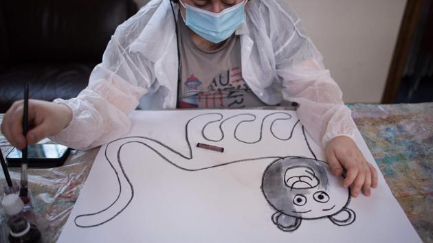 Yago, a young autistic man hosted at the Elan Retrouve association, dedicated to psychiatric disorders in adulthood, paints as he works with an educator, during lockdown, in Paris. Present times pose a difficult situation for persons living with autism as lockdowns and stay-at-home orders upend the routines many individuals are accustomed to. (Loic Venance / AFP)