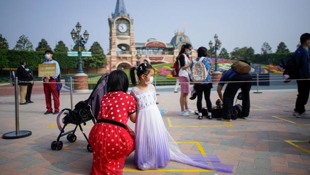 A child looks on while standing inside a marker meant for proper adherence of social distancing in Shanghai Disneyland. Parks, factories and restaurants in cities and countries around the world are reopening under rules to keep customers and workers apart amid the threat of second waves and flare-ups of the virus. (Aly Song / REUTERS)