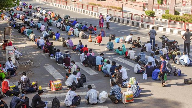 Migrant workers seen sitting on a street as they wait for buses to the railway station in Surat. Last week, the Indian Railway began running special trains for migrants separated from their families on account of the lockdown and them being stranded without any earnings. (PTI) Migrant workers seen sitting on a street as they wait for buses to the railway station in Surat. Last week, the Indian Railway began running special trains for migrants separated from their families on account of the lockdown and them being stranded without any earnings. (PTI)