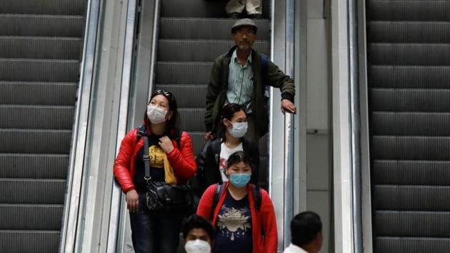 Passengers wearing protective masks travel on an escalator at an airport terminal following an outbreak of the coronavirus disease (COVID-19), in New Delhi, India, March 14, 2020.(REUTERS)