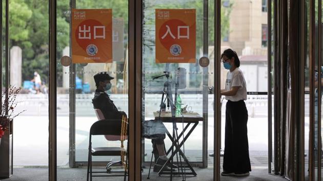 A woman wearing a face mask scans a code at the entrance of a building in Wuhan. With the virus taking hold in other nations, China has barred most foreigners from entering the country. (STR / AFP / China OUT)