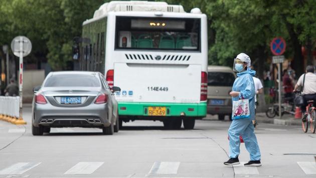 A woman wearing a face shield crosses a street in Wuhan. According to the official national data, Wuhan has 3,869 deaths since the novel coronavirus first emerged in December, accounting for most fatalities in China. (STR / AFP / China OUT)