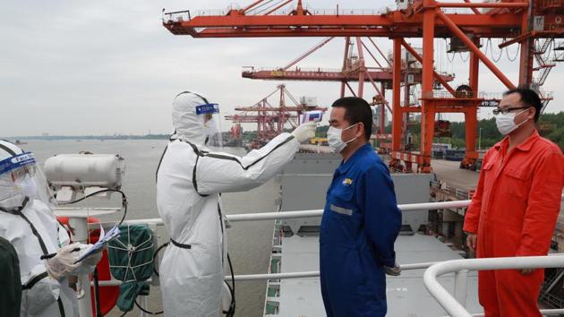 A staff member in protective suit takes body temperature measurement of a crew worker of a cargo ship bound for Japan following the coronavirus disease (Covid-19) outbreak, at a container terminal at a port in Wuhan, Hubei province, China.(REUTERS) A staff member in protective suit takes body temperature measurement of a crew worker of a cargo ship bound for Japan following the coronavirus disease (Covid-19) outbreak, at a container terminal at a port in Wuhan, Hubei province, China.(REUTERS)