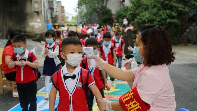 A staff member takes body temperature measurement of schoolchildren at a kindergarten that has resumed operation after Covid-19 lockdown was lifted in China, in Hunan province on May 11. (Reuters Photo) A staff member takes body temperature measurement of schoolchildren at a kindergarten that has resumed operation after Covid-19 lockdown was lifted in China, in Hunan province on May 11. (Reuters Photo)