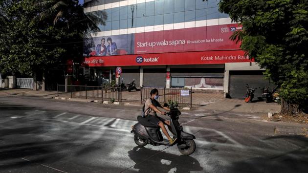 A motorcyclist wearing a protective mask rides past a Kotak Mahindra Bank Ltd. branch on a near-empty street in Mumbai. (Bloomberg) A motorcyclist wearing a protective mask rides past a Kotak Mahindra Bank Ltd. branch on a near-empty street in Mumbai. (Bloomberg)