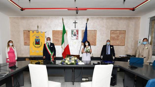 (L to R) Mother and wedding groom witness Francesca Armillota, Briosco’s mayor Antonio Verbicaro, Italian bride Ester Concilio, Italian bridegroom Rafaele Carbonelli, his father and wedding bride witness Francesco Concilio pose for a group picture while maintaining social distance during the wedding ceremony. (Miguel Medina / AFP)