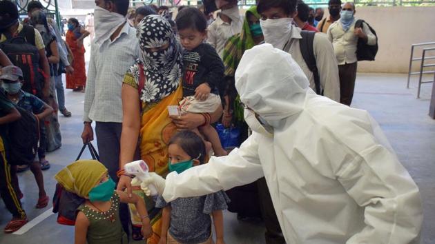 A medic conducts thermal scanning of migrants as they wait to leave the Prayagraj Junction after their arrival from Gujarat by a special train, amid ongoing COVID-19 lockdown in Prayagraj.(PTI) A medic conducts thermal scanning of migrants as they wait to leave the Prayagraj Junction after their arrival from Gujarat by a special train, amid ongoing COVID-19 lockdown in Prayagraj.(PTI)