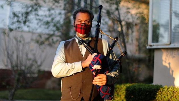 Andrew McGregor, 40, poses for a photo before his evening bagpipe performance of “Amazing Grace” at sunset for the neighborhood.(REUTERS)