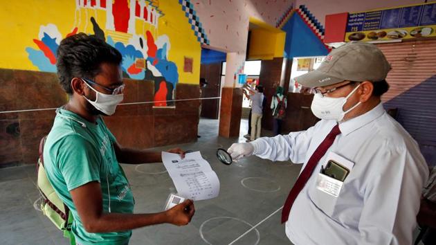A railway officer uses a magnifying glass to check the travel document of a man upon his arrival at a railway station to board a train to New Delhi after a limited reopening of India's rail network on May 12.(Reuters Photo) A railway officer uses a magnifying glass to check the travel document of a man upon his arrival at a railway station to board a train to New Delhi after a limited reopening of India's rail network on May 12.(Reuters Photo)