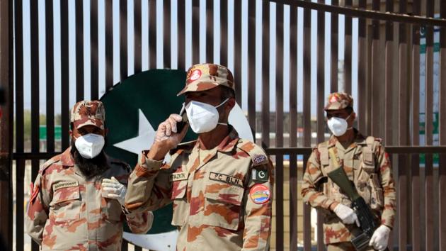 Paramilitary soldiers wear face masks as they stand in front of a closed gate of Pakistan's border post, after Pakistan sealed its border with Iran as a preventive measure following the coronavirus outbreak, at the border post in Taftan. (REUTERS)