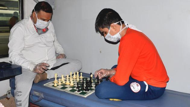 Passengers with their faces covered play chess in a train to New Delhi from Howrah. For now, the Indian Railways is operating only air-conditioned (AC) coaches in these special trains. (ANI) 