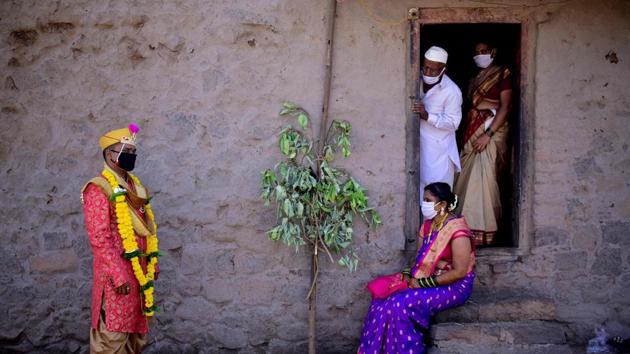 Groom Vitthal Koditkar (L) of Hirpodi village speaks with his bride Vrushali Renuse (R) of Pabe village and family members after their wedding in the middle of a nationwide lockdown, in Pune. (Sanket Wankhade / AFP)