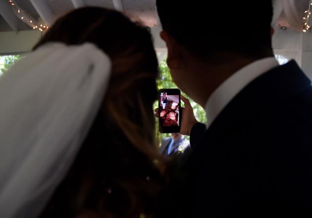 Newly married couple Rachel and Sebastian Vasquez talk (via Facetime) to relatives who could not attend their wedding ceremony on May 9 at the Glencliff Manor in Rustburg, Virginia. The Glencliff Manor officiates free, socially distanced ceremonies for couples left with no wedding plans during the coronavirus pandemic. Only ten people are allowed at each hour-long ceremony. (Olivier Douliery / AFP)