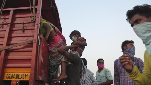 A migrant worker from Chhattisgarh state helps a child climb onto a truck to travel to their villages hundreds of miles away, during a nationwide lockdown to curb the spread of new coronavirus on the outskirts of Hyderabad, India.(AP)