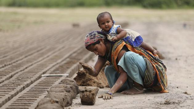 An Indian woman works at a brick kiln as he child plays on her back during lockdown to curb the spread of new coronavirus on the outskirts of Jammu, India.(AP)
