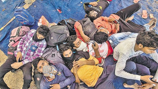 Stranded migrants take rest at a parking lot, violating social distancing norms, as they wait for a bus at Wagholi. (Pratham Gokhale/HT Photo) Stranded migrants take rest at a parking lot, violating social distancing norms, as they wait for a bus at Wagholi. (Pratham Gokhale/HT Photo)
