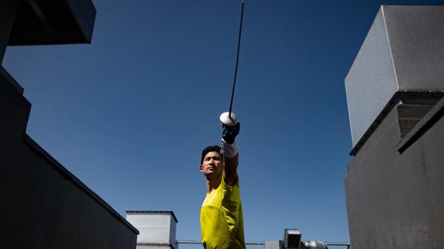 Japanese fencer Ryo Miyake works out with a foil on the rooftop of a building in Tokyo. (Philip Fong / AFP)