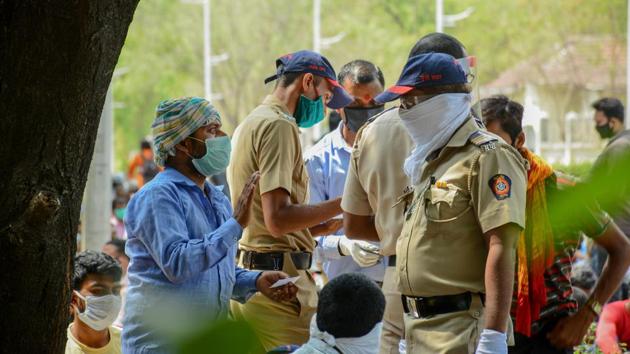 A migrant in conversation with a Chatushrungi police personnel before leaving by bus to Pune railway station to catch a Shramik Special train, in Pune on May 13, 2020.(Milind Saurkar/HT Photo)