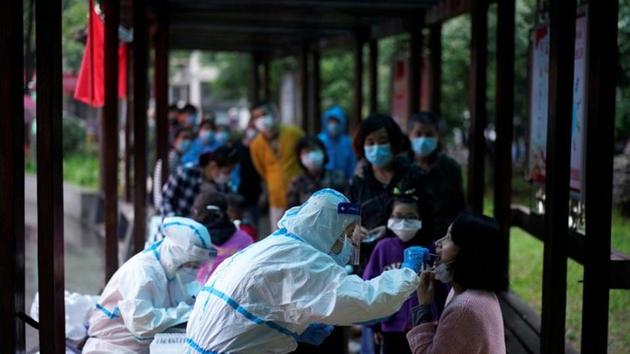A medical worker in a protective suit conducts a nucleic acid testing for a resident as people wearing face masks queue behind for testings, at a residential compound in Wuhan, the Chinese city hit hardest by the coronavirus disease (COVID-19) outbreak, Hubei province, China May 14, 2020. REUTERS/Aly Song (REUTERS) A medical worker in a protective suit conducts a nucleic acid testing for a resident as people wearing face masks queue behind for testings, at a residential compound in Wuhan, the Chinese city hit hardest by the coronavirus disease (COVID-19) outbreak, Hubei province, China May 14, 2020. REUTERS/Aly Song (REUTERS)