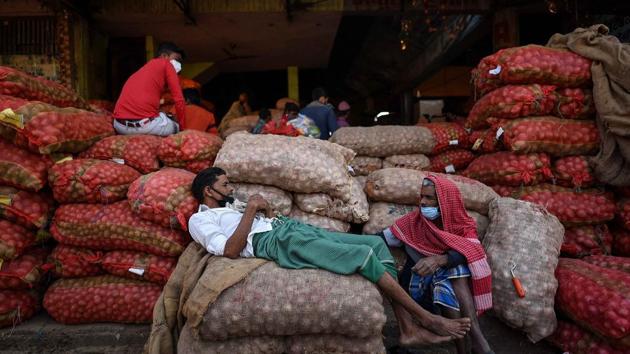 Labourers resting on sacks of onions in Okhla Mandi, New Delhi.(Biplov Bhuyan/HT PHOTO)