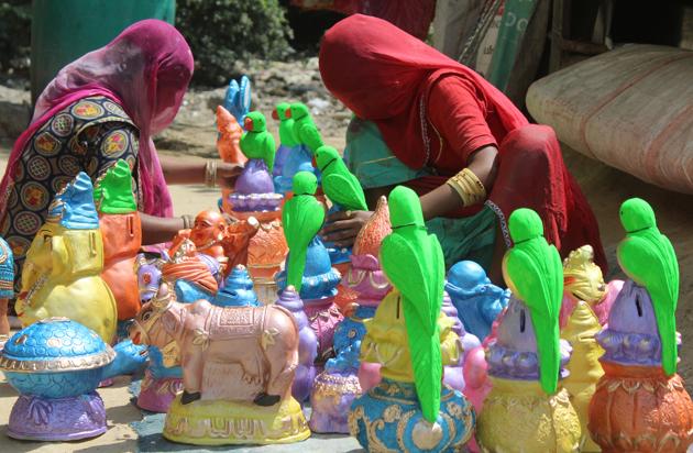 Women arrange idols at the roadside, during lockdown to curb the spread of coronavirus, at Vyapar Sadan, MG road, in Gurugram, on May 12, 2020. The workers who hail from Rajasthan haven't left the city and are hoping that people will buy products from them as the district administration eases rules during lockdown.(Yogendra Kumar/HT PHOTO)