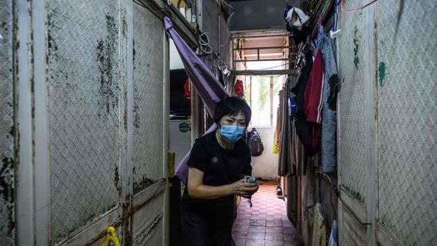 Wong Mei-ying walks in a shared corridor outside her 50-square feet cubicle flat, where she lives and shares a bunk bed with her 43-year old son. Hers is a walk-up flat that has been subdivided into six cubicles in the New Territories of Hong Kong. (Anthony Wallace / AFP) Wong Mei-ying walks in a shared corridor outside her 50-square feet cubicle flat, where she lives and shares a bunk bed with her 43-year old son. Hers is a walk-up flat that has been subdivided into six cubicles in the New Territories of Hong Kong. (Anthony Wallace / AFP)