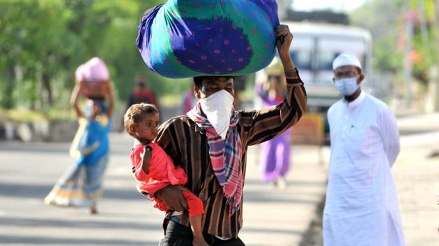 A man with a child in his arms and a bundle on his head walks towards the railway station to board a train to Delhi, in Jammu city, Jammu and Kashmir, India on Friday, May 15, 2020. (Photo by Nitin Kanotra / Hindustan Times) A man with a child in his arms and a bundle on his head walks towards the railway station to board a train to Delhi, in Jammu city, Jammu and Kashmir, India on Friday, May 15, 2020. (Photo by Nitin Kanotra / Hindustan Times)