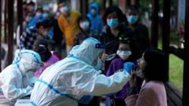 A medical worker in a protective suit conducts a nucleic acid testing for a resident as people wearing face masks queue behind for testings, at a residential compound in Wuhan, the Chinese city hit hardest by the coronavirus disease (COVID-19) outbreak, Hubei province, China (REUTERS) A medical worker in a protective suit conducts a nucleic acid testing for a resident as people wearing face masks queue behind for testings, at a residential compound in Wuhan, the Chinese city hit hardest by the coronavirus disease (COVID-19) outbreak, Hubei province, China (REUTERS)